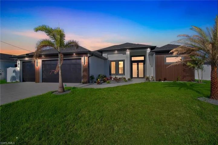 View of front facade featuring driveway, a front yard, and an attached garage