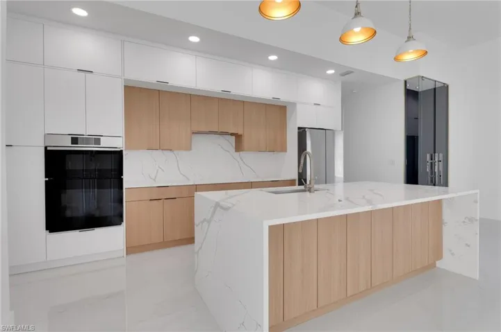 Kitchen with modern cabinets, light stone countertops, recessed lighting, white cabinets, and pendant lighting