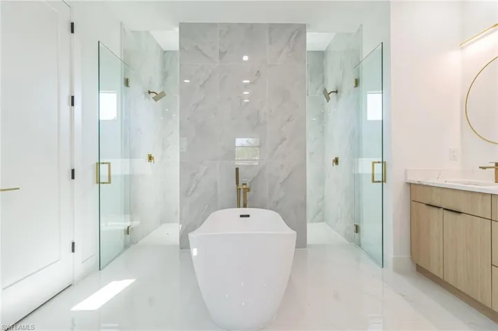 Full bath with double vanity, a marble finish shower, a soaking tub, recessed lighting, and light marble finish floors