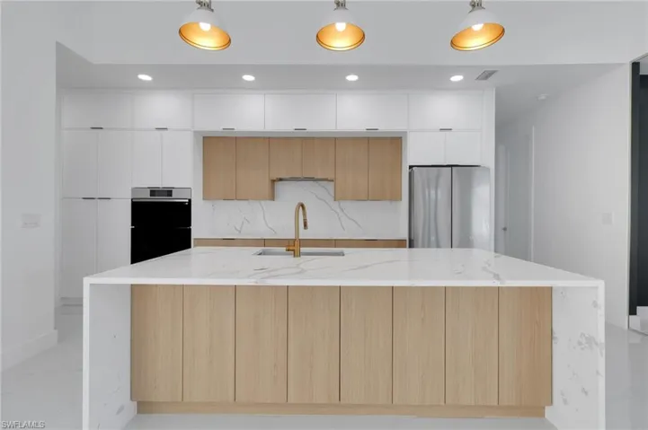 Kitchen with modern cabinets, hanging light fixtures, recessed lighting, appliances with stainless steel finishes, and backsplash