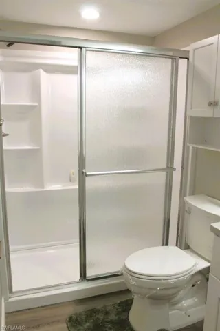 Full bath featuring light wood-type flooring, a shower stall, and vanity