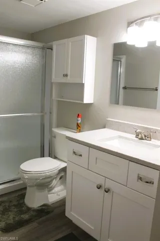 Bathroom featuring a stall shower, vanity, dark wood finished floors, baseboard heating, and a textured wall
