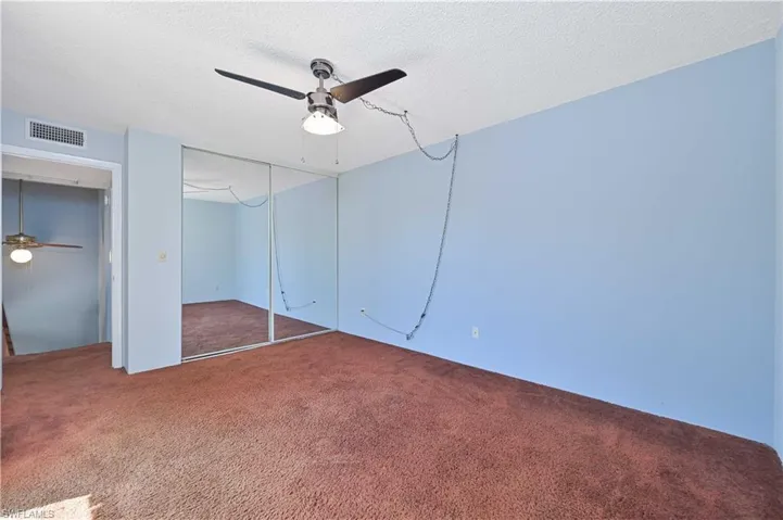 Unfurnished bedroom with carpet floors, a textured ceiling, a closet, and ceiling fan