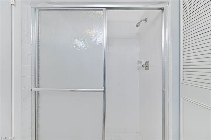 Bathroom with a shower stall and a closet