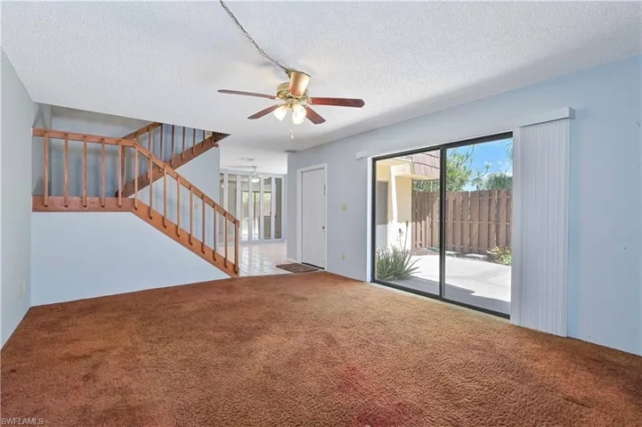 Unfurnished living room with plenty of natural light, a textured ceiling, ceiling fan, and carpet floors