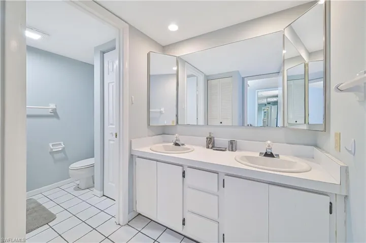 Bathroom featuring a closet, double vanity, and light tile patterned floors