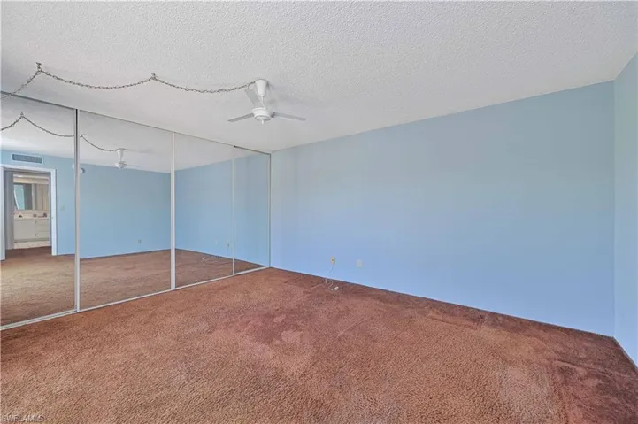 Unfurnished bedroom featuring carpet flooring, a closet, a textured ceiling, and a ceiling fan