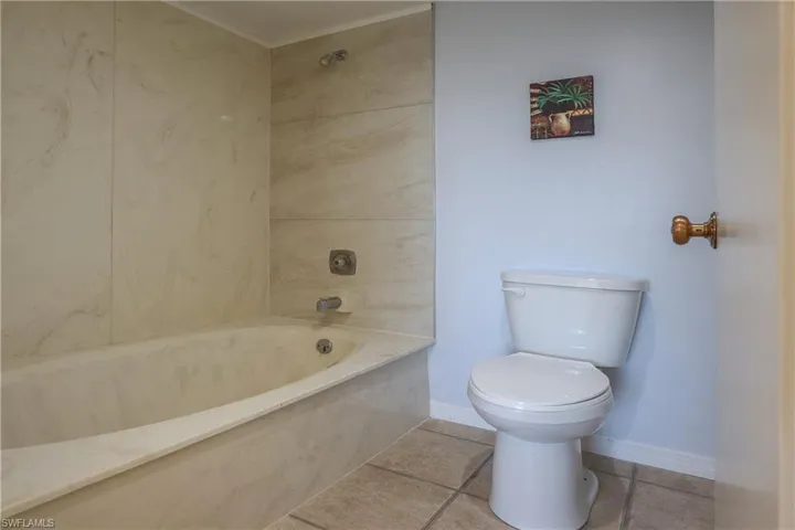 Full bathroom with a combined bath / shower with marble appearance and tile patterned floors
