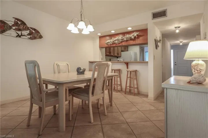 Dining area featuring light tile patterned flooring, recessed lighting, and a chandelier