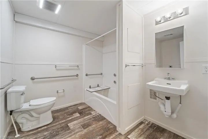 Full bath featuring toilet, wood finished floors, tub / shower combination, and baseboards