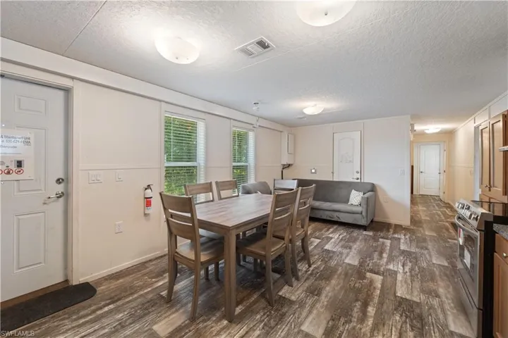 Dining space with dark wood-type flooring, a textured ceiling, and baseboards