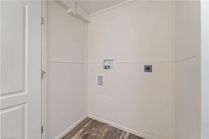 Laundry area with electric dryer hookup, hookup for a washing machine, dark wood-style floors, and baseboards