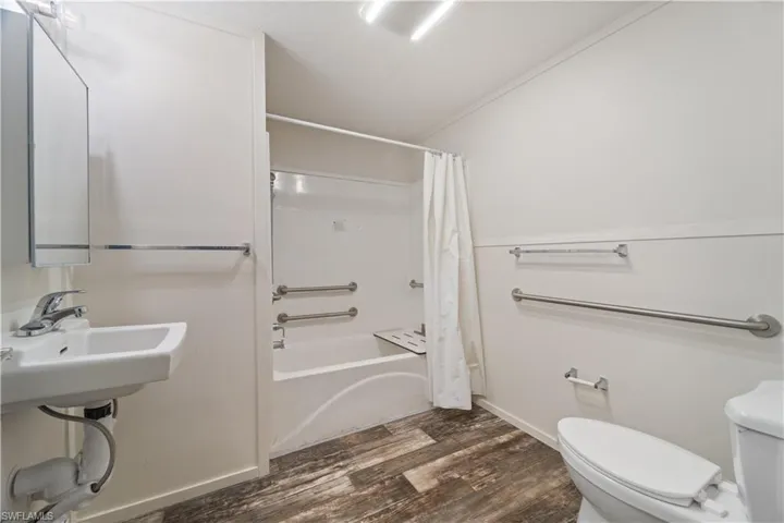 Bathroom featuring toilet, wood finished floors, and shower / bath combo