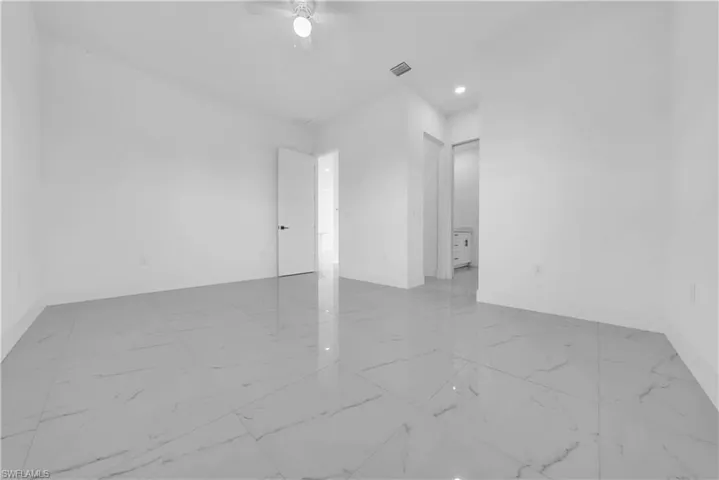 Empty room featuring ceiling fan, recessed lighting, and light marble finish flooring