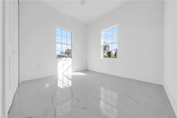 Spare room featuring light marble finish floors and baseboards