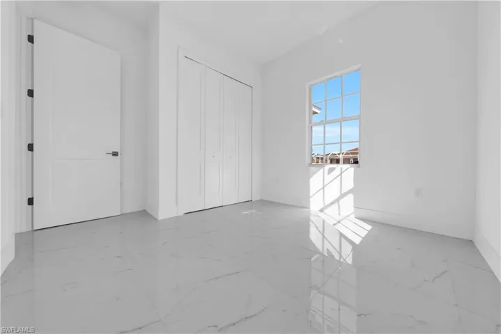 Unfurnished bedroom with a closet and light marble finish floors