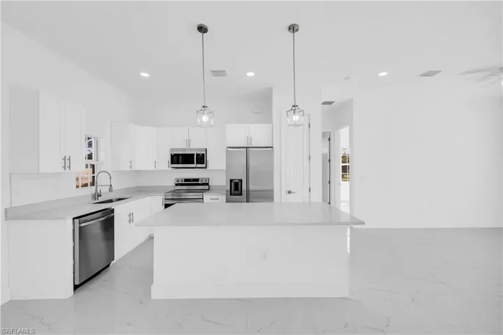 Kitchen featuring stainless steel appliances, a center island, white cabinetry, light stone countertops, and decorative backsplash