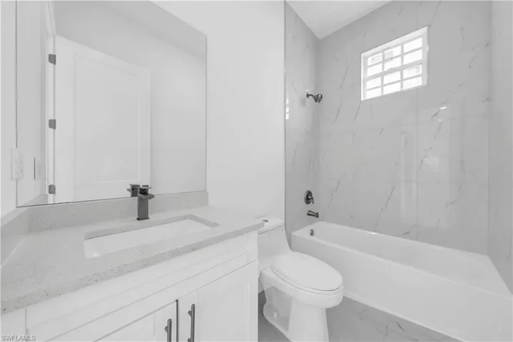 Full bath featuring vanity, shower / washtub combination, and marble look tile flooring