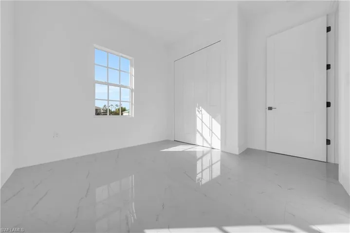 Unfurnished bedroom with a closet and light marble finish flooring