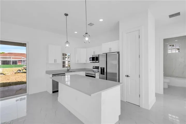 Kitchen with healthy amount of natural light, stainless steel appliances, a center island, and white cabinets