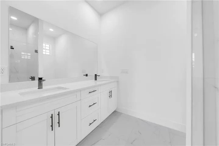 Full bathroom with a marble finish shower, double vanity, light marble finish floors, and recessed lighting