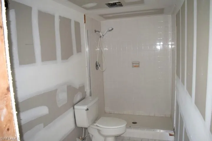 Bathroom with tiled shower, tile patterned floors, and toilet