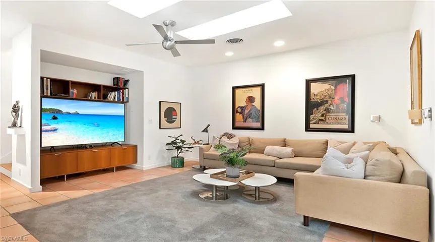 Living area with a skylight, light tile patterned floors, ceiling fan, and recessed lighting