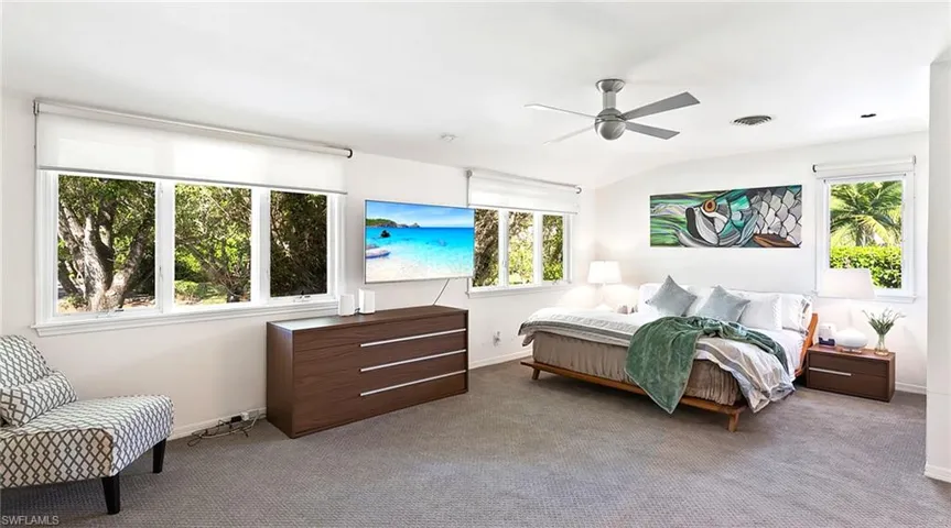 Carpeted bedroom with multiple windows and ceiling fan