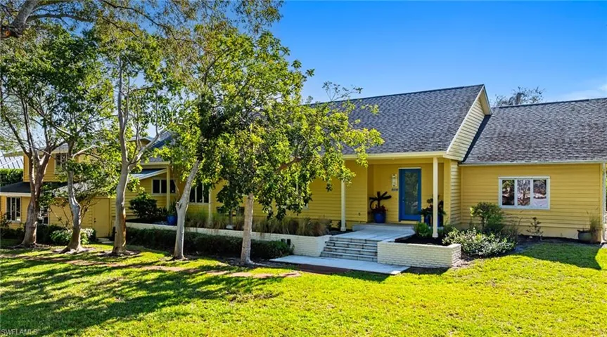 Rear view of house featuring roof with shingles and a yard