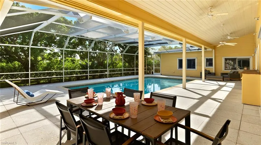 View of pool with a lanai, a patio, a sunroom, and outdoor dining space