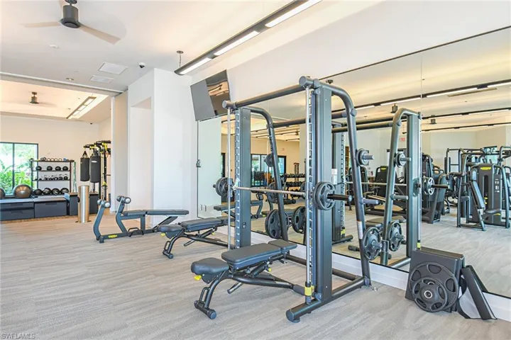 Exercise room with ceiling fan and light carpet