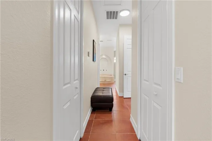 Bedroom featuring ornamental molding, light tile patterned floors, a tray ceiling, and ensuite bath