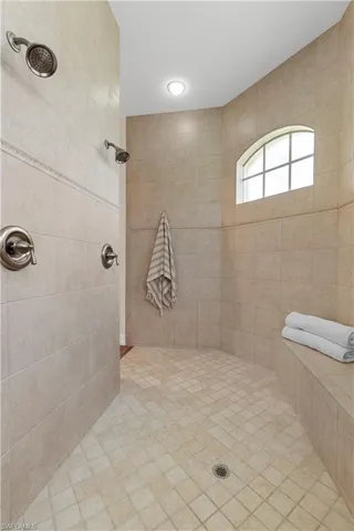 Full bath with tiled shower, healthy amount of natural light, and tile walls