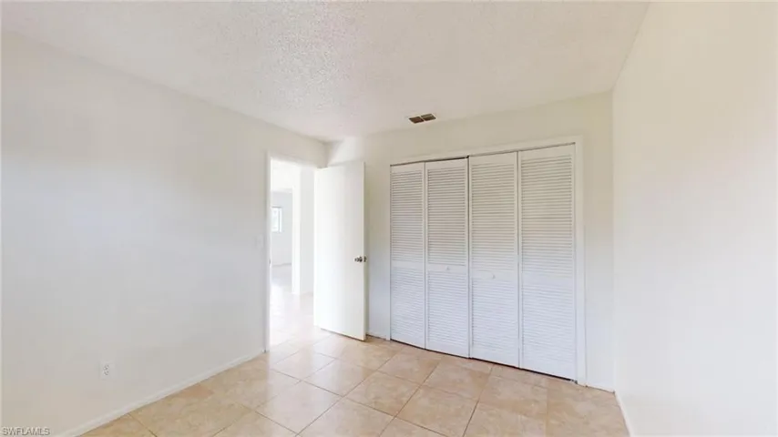 Unfurnished bedroom featuring light tile patterned flooring, a closet, and a textured ceiling