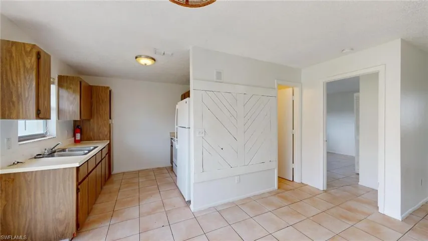 Kitchen with light tile patterned flooring, sink, and white fridge