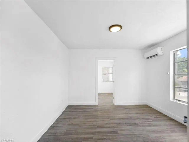 Unfurnished room featuring dark wood-style flooring and baseboards