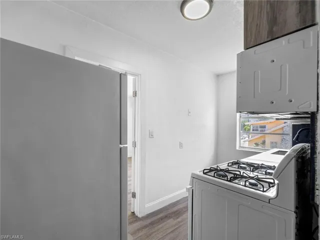 Kitchen featuring freestanding refrigerator, white gas range oven, wood finished floors, and a textured ceiling
