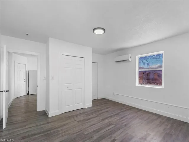 Unfurnished bedroom with dark wood-style floors and a closet
