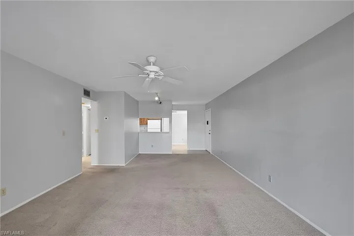 Unfurnished living room with light carpet and a ceiling fan