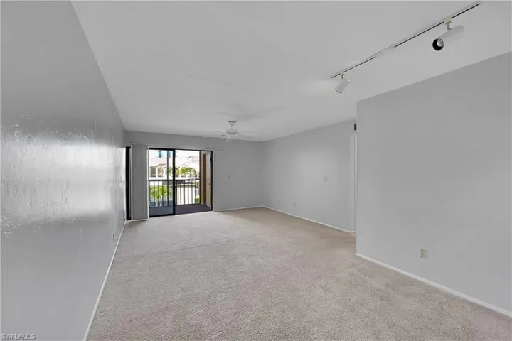 Unfurnished room with light colored carpet, rail lighting, and ceiling fan