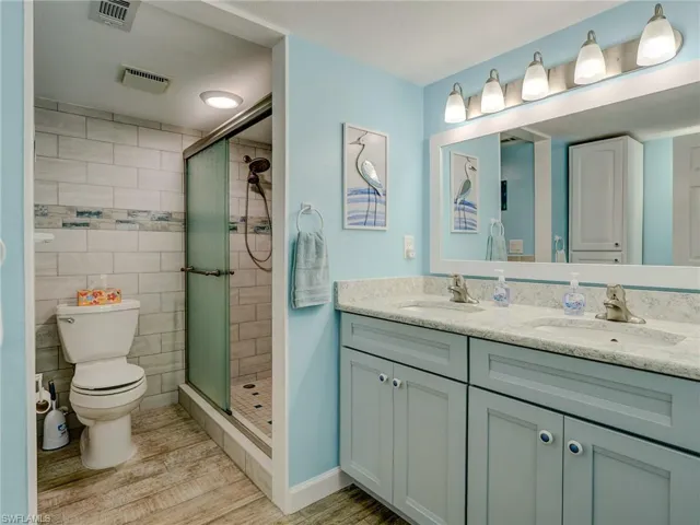 Bathroom featuring vanity, hardwood / wood-style flooring, a shower with shower door, and toilet