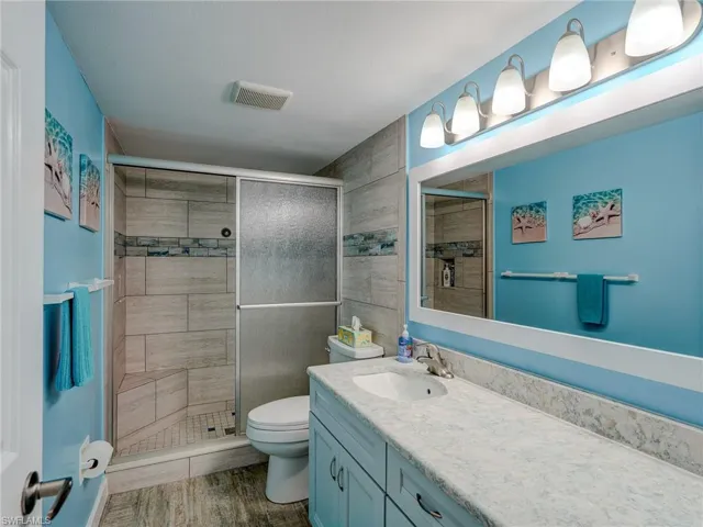 Bathroom with vanity, wood-type flooring, a shower with door, and toilet