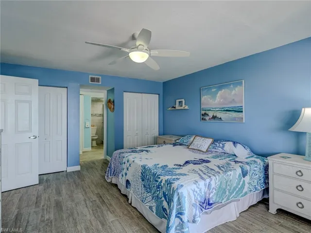 Bedroom with ceiling fan, wood-type flooring, and two closets