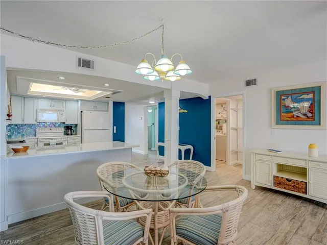 Dining space with a notable chandelier, light hardwood / wood-style floors, and ornate columns