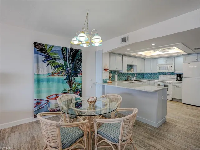 Dining space featuring sink, a tray ceiling, light hardwood / wood-style flooring, and a notable chandelier