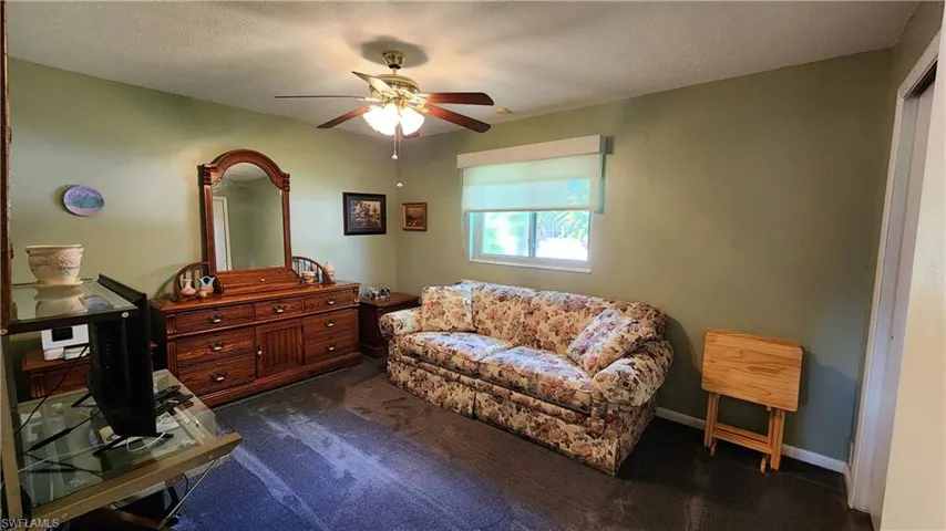 Living area with carpet, ceiling fan, and a textured ceiling