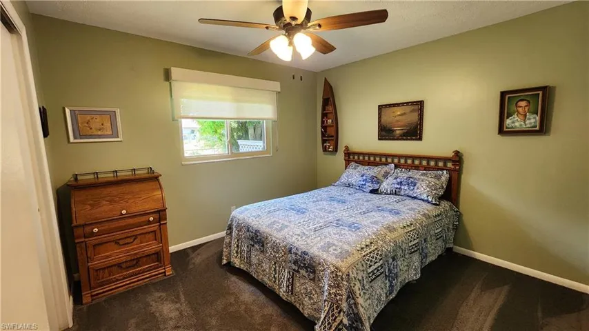 Bedroom with ceiling fan and dark colored carpet