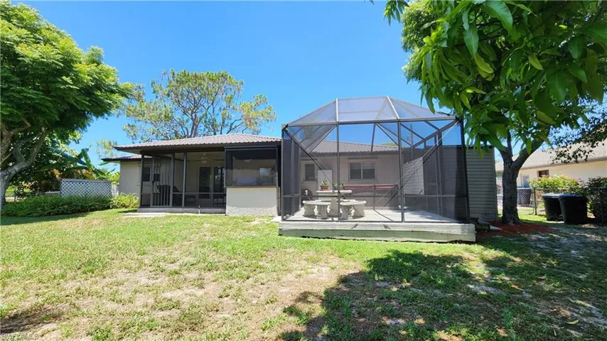 Back of house featuring a lawn and glass enclosure