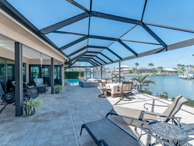 View of patio with a lanai, a water view, an outdoor living space, and a pool with connected hot tub