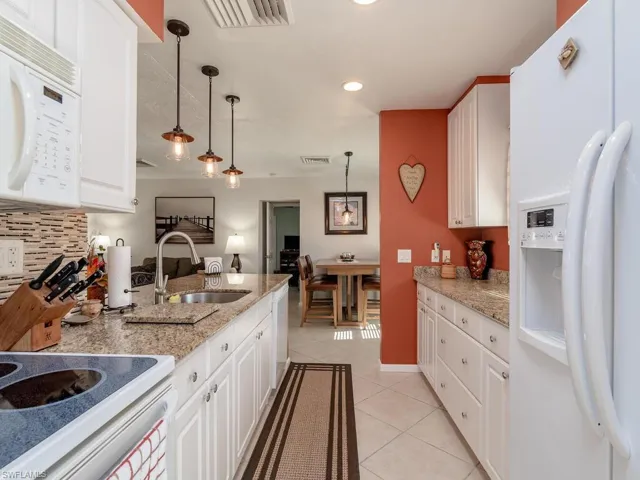 Kitchen featuring white appliances, a sink, light tile patterned floors, recessed lighting, and white cabinets